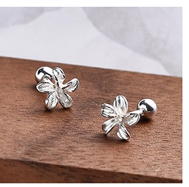 Macro view of S925 silver flower stud earrings on a wooden surface with a smooth ball back