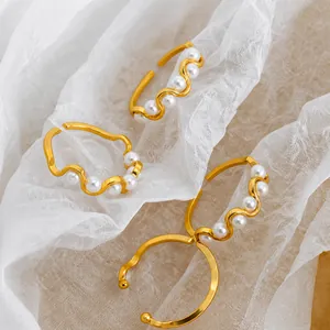 Detail eines verstellbaren Goldwellenrings mit weißen runden Perlen auf weißem Stoff