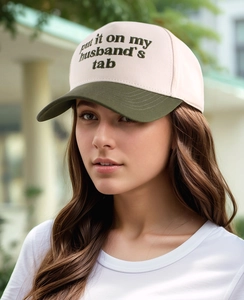 Detail of embroidered text on a pink and dark green contrast cotton baseball cap