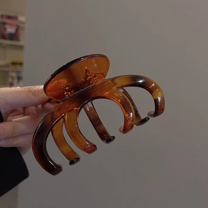 Detailed close-up of large amber tortoiseshell hair claw clip held in hand for size display
