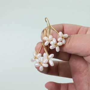 Close-up of golden flower earrings with white freshwater pearls and small diamonds