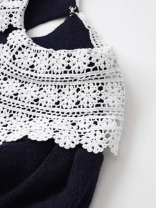 Detailed close-up of a navy knit collar with white lace trim and silver metal buckle