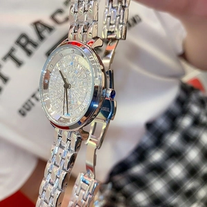 Macro shot of silver crystal-encrusted watch dial with blue crown and stainless steel strap