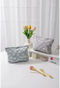 Détails de broderies florales sur trousses de maquillage en toile de coton gris et mauve