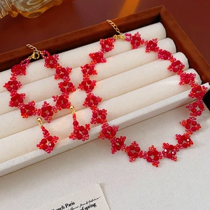 Detail of red beaded jewelry set with flower pattern in a beige velvet jewelry box