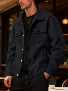 Detail of black corduroy shirt jacket featuring dual chest pockets and metal buttons