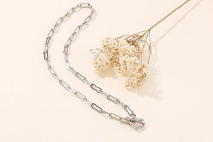 Close-up of silver paperclip chain necklace with heart OT toggle clasp and floral decor