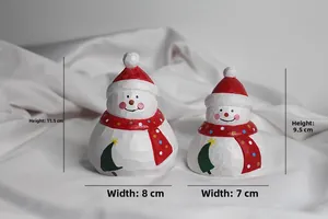 Detail of two resin snowman figurines with wood carving texture and red polka dot scarves