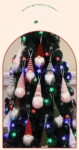 Close-up of knitted Christmas gnome ornaments with long hats hanging on a tree