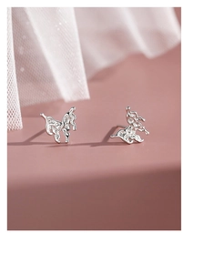 Macro detail of silver lava butterfly earrings on soft pink silk and white lace