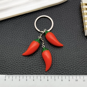 Realistic red resin chili keychain with three pendants on metal ring over black leather