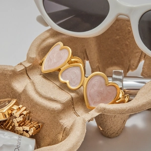 Detail of pink enamel heart modules on a gold titanium steel bracelet with a polished finish