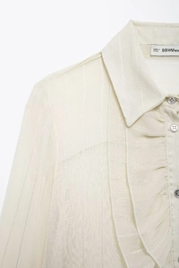 Detail of ruffle collar and textured fabric on a French style beige women blouse