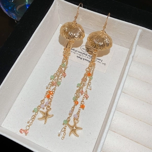 Vue détaillée des boucles d'oreilles dorées à glands avec méduses et perles colorées
