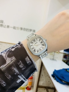 Detail of silver steel watch with Roman numerals and rectangular dial on a wrist
