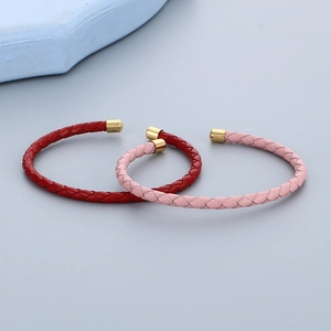 Dettaglio dei bracciali in pelle intrecciata rossi e rosa con chiusure dorate