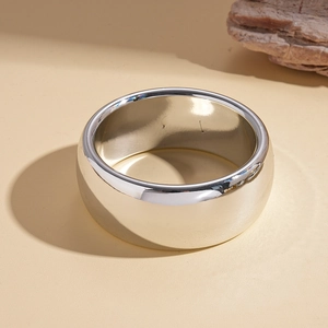Macro shot of minimalist wide polished gold metal bangle with reflective surface