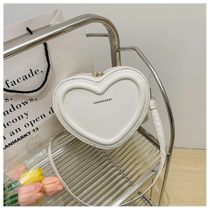 Dettaglio della borsa a tracolla in pelle bianca a forma di cuore su supporto argento