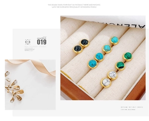 Close-up of five pairs of colorful round gemstone stud earrings in a beige velvet box
