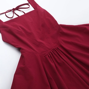 Detail of burgundy backless dress with square neck and tie-up halter straps on white background
