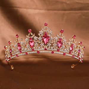 Detailed view of a golden bridal crown with sparkling rhinestones and pink gems on fabric