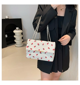 Détail du sac en velours côtelé à imprimé fraise avec chaîne dorée sur un blazer