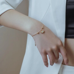 Elegant gold titanium steel bracelet with heart mother of pearl pendant worn on wrist