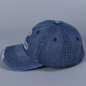 Detail view of a distressed denim baseball cap with frayed edges and letter embroidery