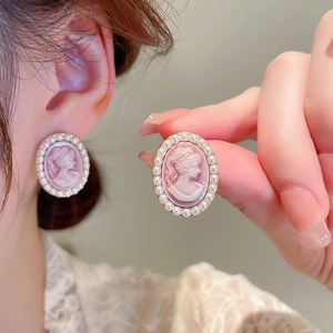 Detail of vintage pink cameo earrings featuring an oval portrait and elegant pearl border