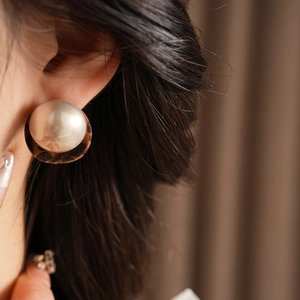 Close-up of a large leopard print earring with a glossy center pearl on a female model