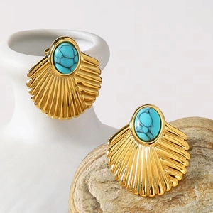 Luxurious turquoise shell fan earrings in gold titanium steel on a white ceramic vase