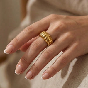 Detail of a chunky gold-tone ribbed dome ring on a finger with minimalist texture
