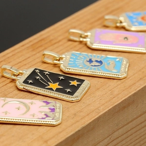 Close-up of gold-plated tarot card pendants with colorful enamel star and moon designs