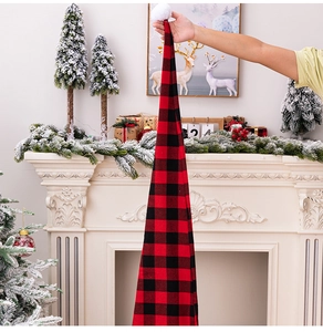 Extra long red and black plaid Santa hat with white pom-pom in a festive fireplace scene