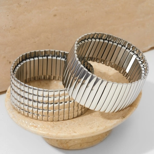 Silver stretch snake bone bracelet with ribbed metal texture on stone pedestal