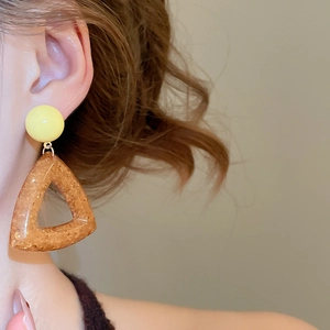Detailed macro view of resin geometric earrings with gold foil on a female model