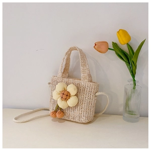 Detail of beige straw handbag featuring a large floral ornament and versatile shoulder strap
