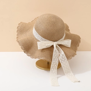 Straw sun hat with white lace bow and scalloped brim for summer beach protection