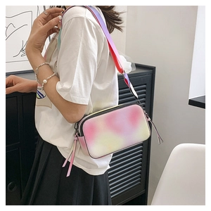 Detail of colorful gradient crossbody camera bag with wide strap worn by a model