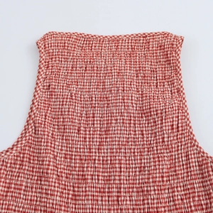 Detailed close-up of red and white plaid smocked fabric texture on sleeveless dress