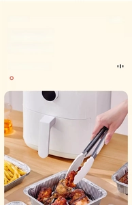 Close-up of silicone head tongs picking up food from an air fryer aluminum foil tray
