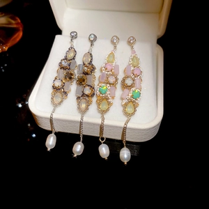 Close-up of luxury drop earrings with colorful stones, opal, and waterdrop pearl details