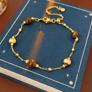 Gold plated bracelet featuring tiger eye beads and textured metallic spheres on a jewelry box