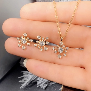 Detail von Schneeflocken-Anhänger und Ohrsteckern in Roségold auf der Hand des Modells