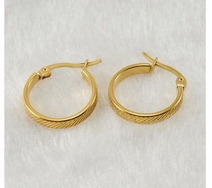 Macro detail of gold-plated stainless steel hoop earrings with textured diagonal pattern
