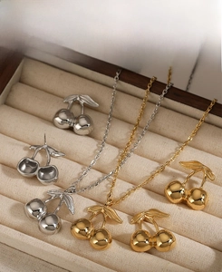 Detailed view of cherry pendant necklace and earrings set in gold and silver finish