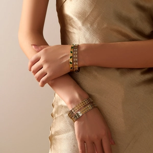 Elegant 18k gold and silver titanium steel bangles with green gemstones on female model
