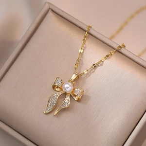 Elegante goldene Schleifen-Halskette mit Perle und Zirkon-Inlay in einer Schmuckschatulle