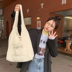 Close-up of beige plush tote bag featuring green Lucky embroidery and orange smiley face