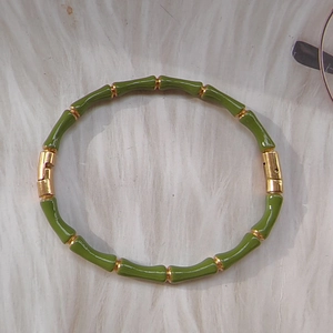 Bamboo-style bangle with green enamel and 18k gold plating on soft white plush
